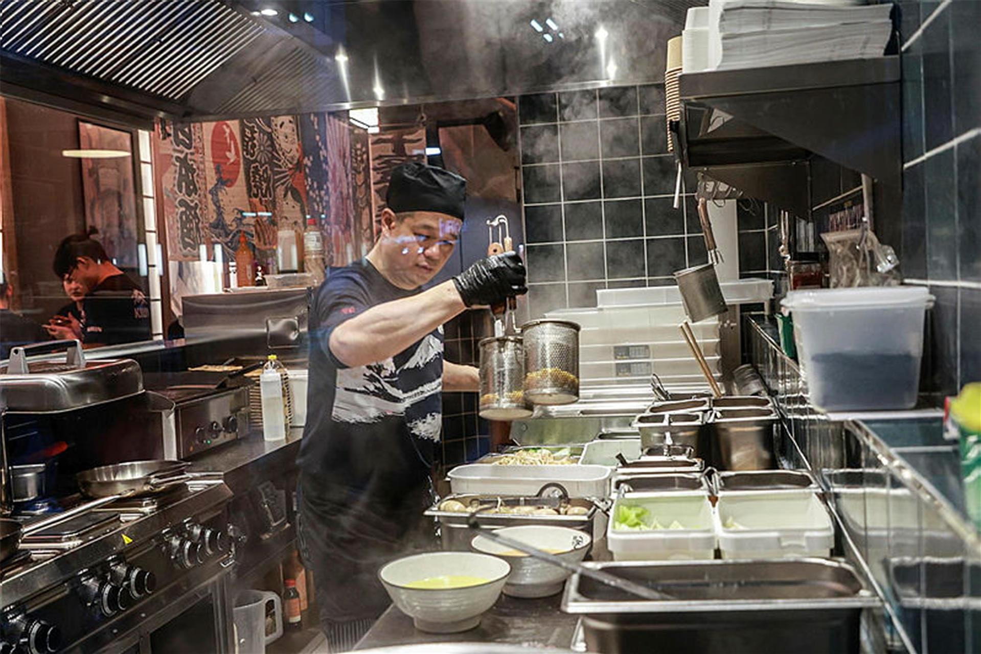 Koch bereitet Ramen in der offenen Küche von Takumi Dortmund zu, Dampf steigt auf